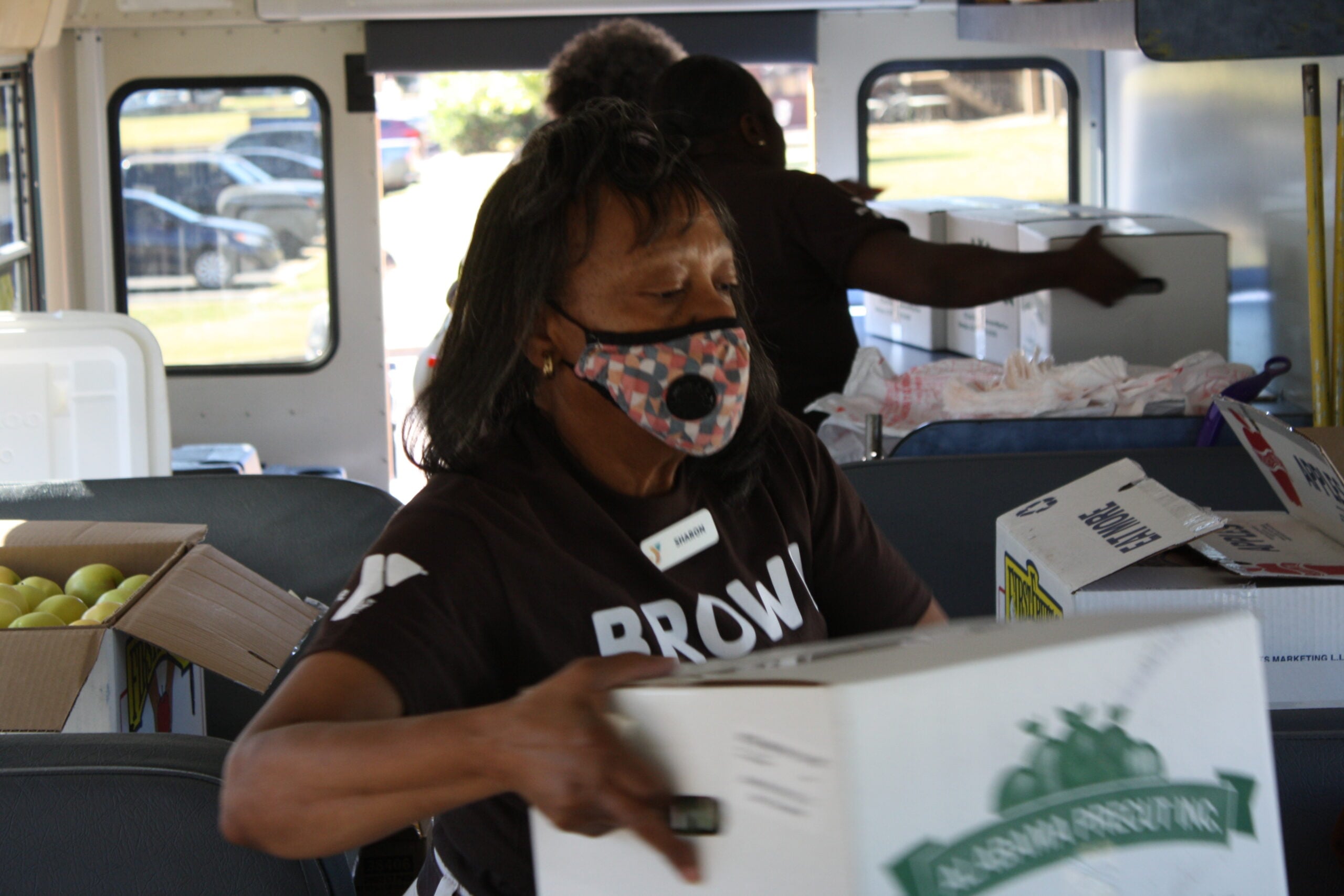 A woman inside the YMCA Brown Bag Bus loads and organizes food donated from Faulkner's Culinary Management team.