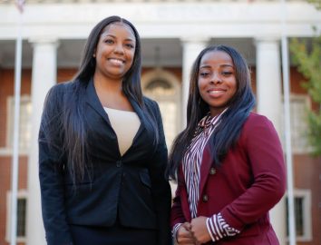 Faulkner Law graduate Aigner Kolom, left poses with Faulkner Law student Iesha Brooks in front of Montgomery City Hall.